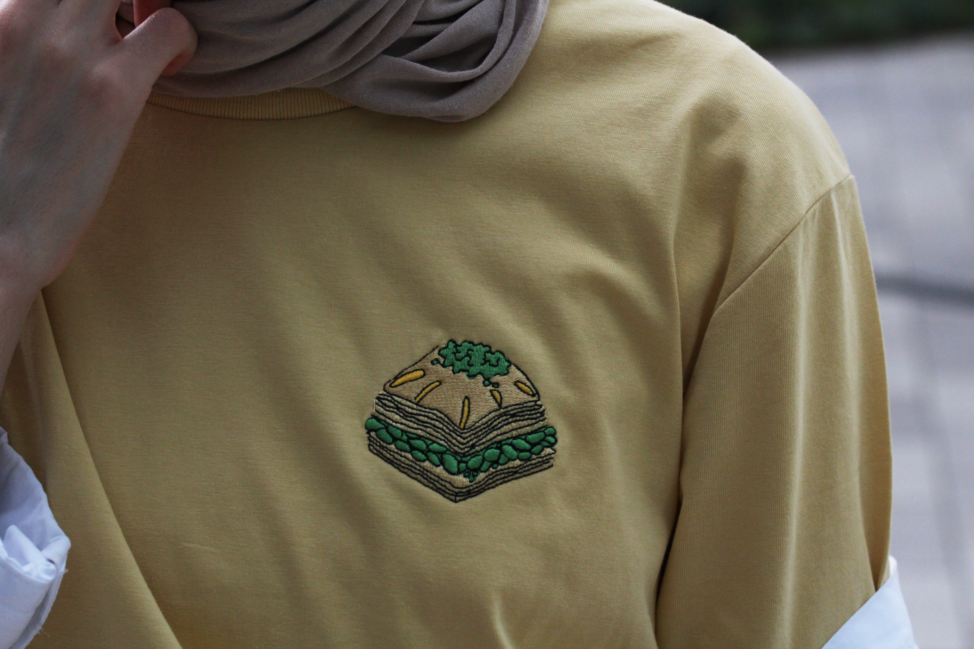 Nachhaltiges Baklava T-Shirt aus Bio-Baumwolle in gelb. Auf der linken Brust ist ein Stück Baklava gestickt.